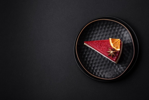 Delicious sweet cheesecake with raspberry jam on a black ceramic plate on a dark concrete background