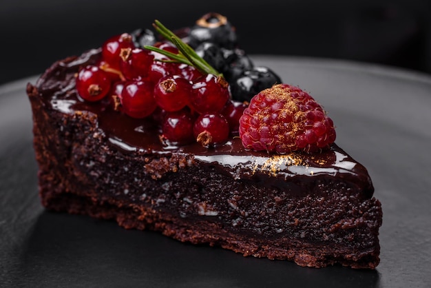 Delicious sweet chocolate brownie cake with blueberries currants and raspberries on a ceramic plate