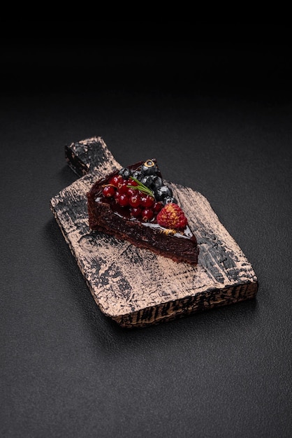 Delicious sweet chocolate brownie cake with blueberries currants and raspberries on a ceramic plate