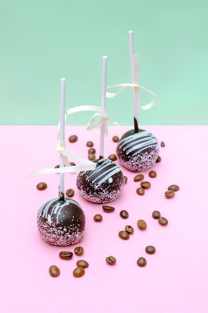 Photo delicious sweet chocolate cake pops decorated white sprinkles coffee beans on pink green background pastry desserts on stick copy space tasty food still life