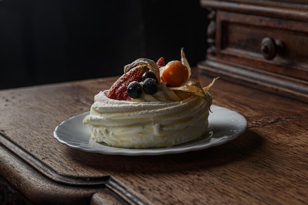 Delicious sweet cream cake on wooden table in the dark