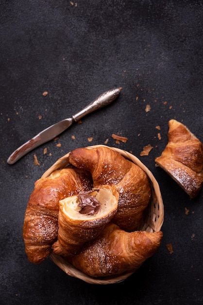 Delicious sweet croissant with chocolate on dark background