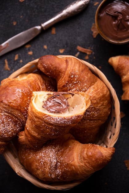 Delicious sweet croissant with chocolate on dark background