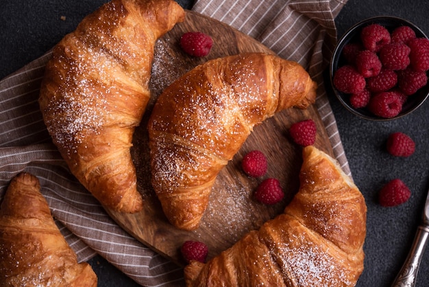 Delicious sweet croissant with fresh fruit on dark background