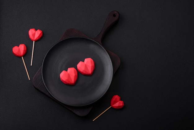 Вкусные сладкие шоколадные конфеты в форме сердца на темном бетонном фоне