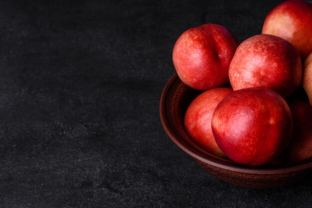 Delicious sweet peaches or nectarines in a brown bowl