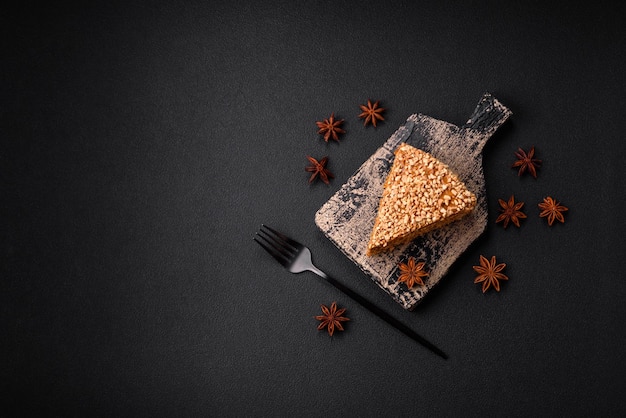 Вкусный сладкий слоеный вафельный торт со сливками и орехами, нарезанный кусочками на текстурированном бетонном фоне