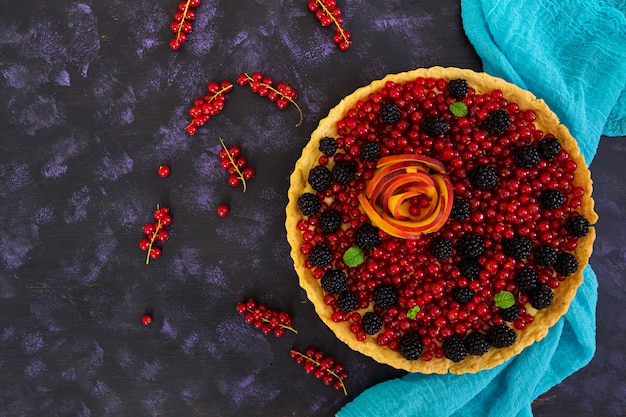 Delicious tart with red currants, peach and blackberries. Top view