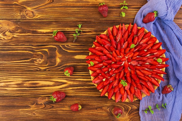 Delicious tart with strawberry on wooden background