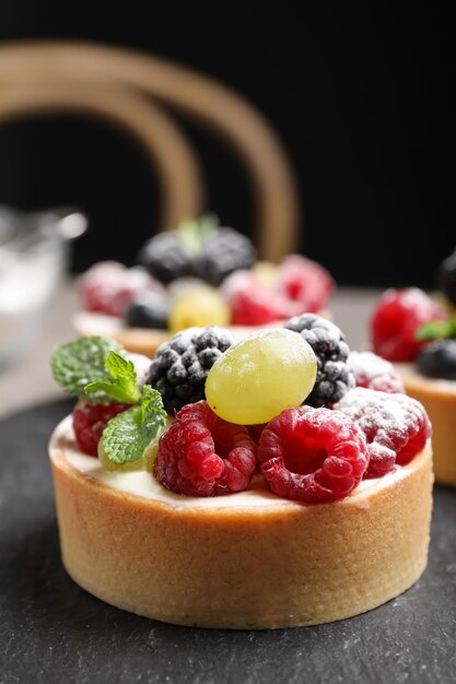 Фото Вкусная тарталетка с ягодами на грифельной доске крупным планом