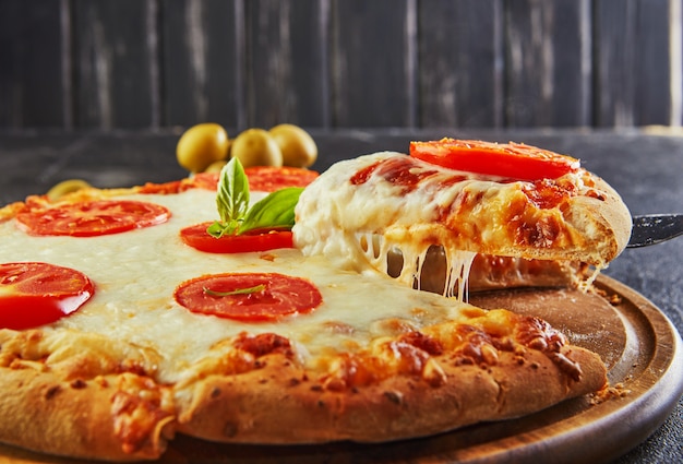 The delicious taste of pizza and slices of cheese with mozzarella and tomatoes. Triangle pizza with stretching cheese and spices