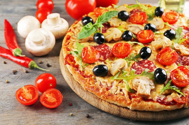 Delicious tasty pizza with ingredients on wooden table