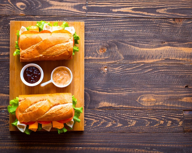 Delicious and Tasty sandwiches with turkey, ham, cheese, tomatoes on wooden background