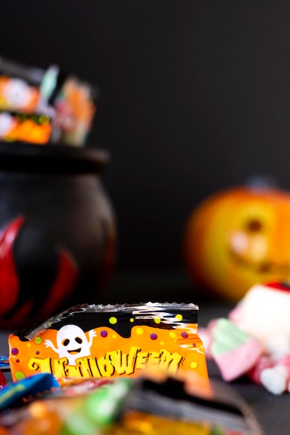 Delicious and terrifying candies ready to eat during the Halloween party, next to a pumpkin, a cauldron, vertical shot, close up, selective focus.