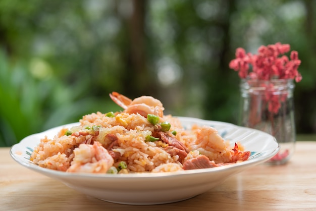 Delicious Thai fried rice with shrimp on wooden table with beauitful vase