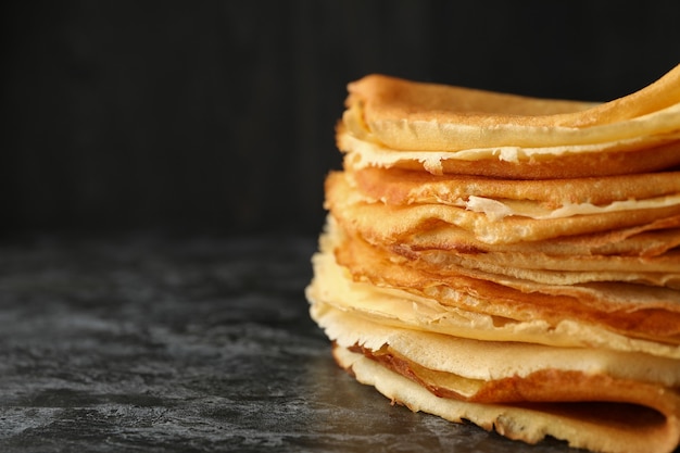 Delicious thin pancakes on black smokey background