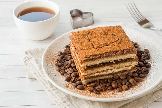 プレートとカップにコーヒー豆とおいしいティラミスケーキ