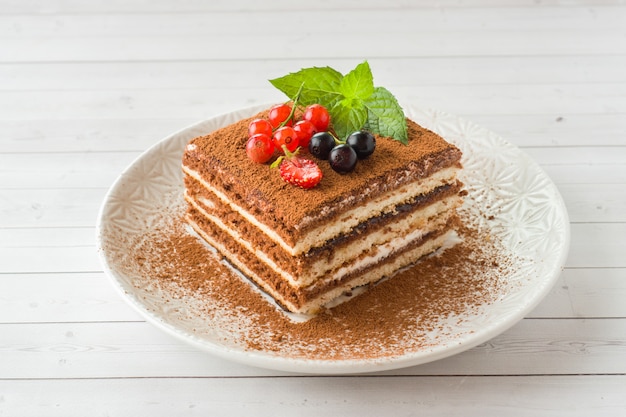 Delicious Tiramisu cake with fresh berries and mint on a plate