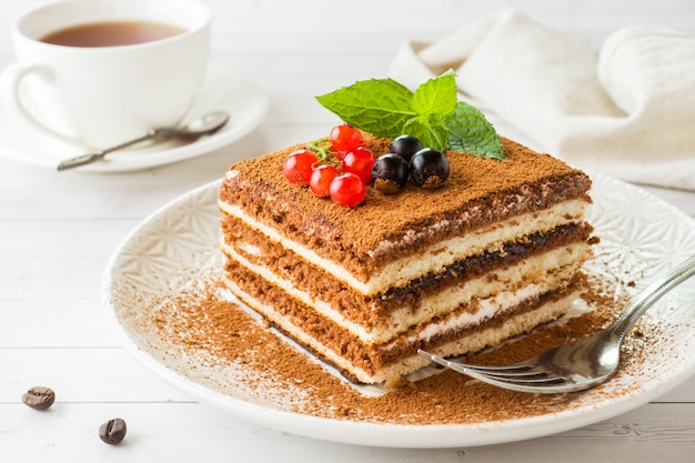 Delizioso dolce tiramisù con frutti di bosco freschi e menta su un piatto