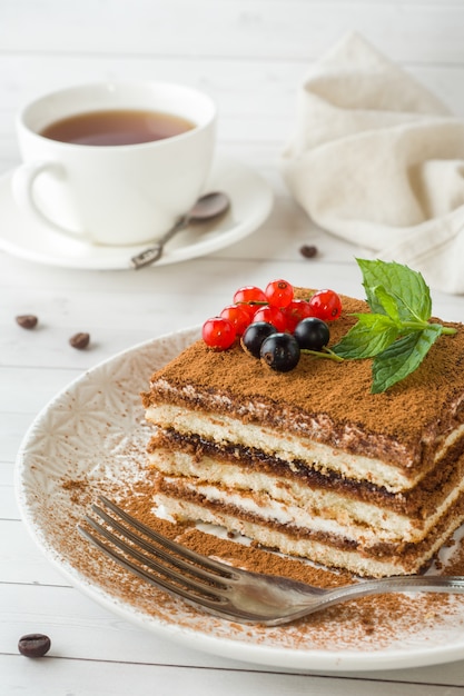 Delicious Tiramisu cake with fresh berries and mint on a plate