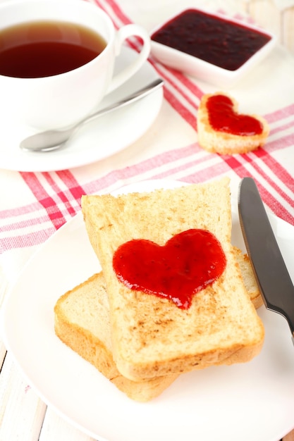 Delicious toast with jam and cup of tea on table close-up