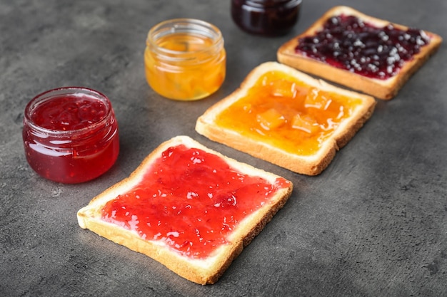 Delicious toasts with various sweet jams on grey background