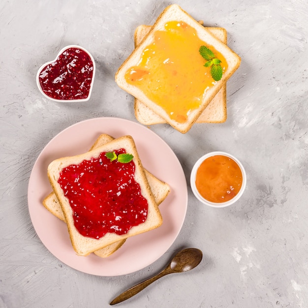 Delicious toasts with various sweet jams on grey