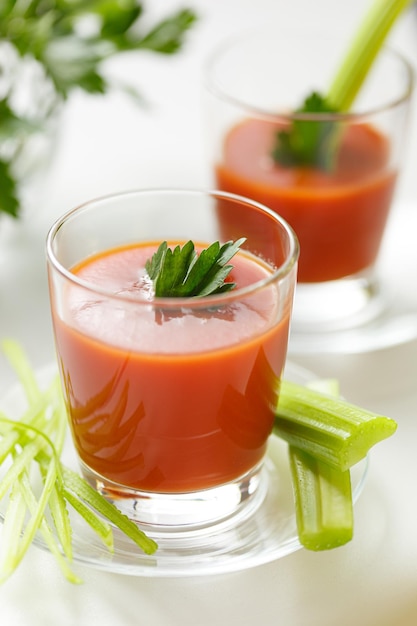 Delizioso succo di pomodoro versato in un bicchiere con prezzemolo e sedano