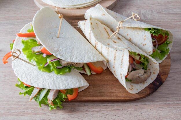 Delicious tortillas with chicken fillets and vegetables on the kitchen board and wooden table dietary nutrition