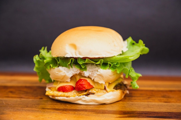 Delicious traditional Brazilian burger X all sausage egg tomato cheese and salad on wooden board