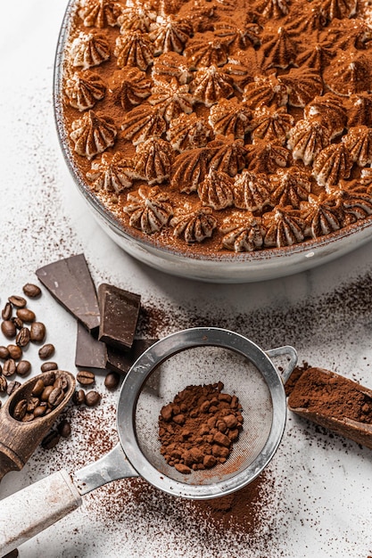 Delizioso tradizionale tiramisù dolce fatto in casa dalla classica ricetta italiana biscotti savayardi caffè cioccolato e cacao su fondo di marmo bianco tiramisù dolce