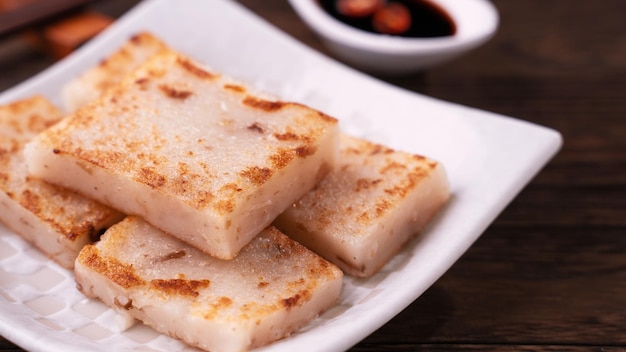 Delicious turnip cake Chinese traditional local dish radish cake in restaurant with soy sauce and chopsticks close up copy space