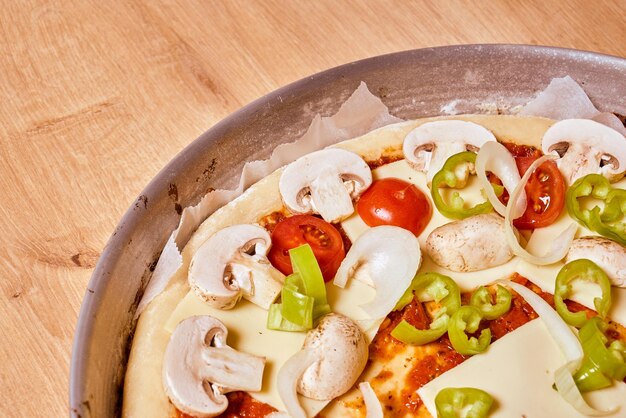 Delicious uncooked vegetarian pizza with mushroom onion mozzarella and green pepper wooden table