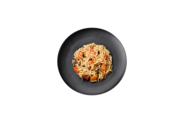Foto delizioso pilaf uzbeko con pollo, carote, crespino, spezie ed erbe su uno sfondo di cemento scuro