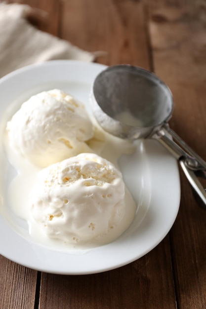 Foto delizioso gelato alla vaniglia sul piatto su fondo di legno