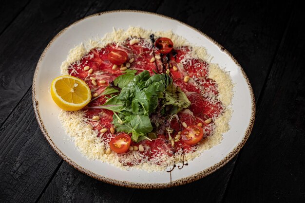 delicious veal carpaccio on a plate on a dark wooden table