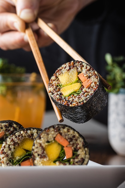 Delicious vegan sushi roll with wooden chopsticks