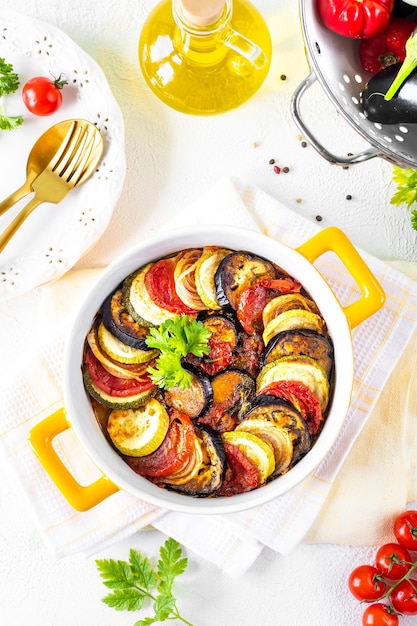 Delicious vegetable ratatouille in a white baking dish on a wooden background