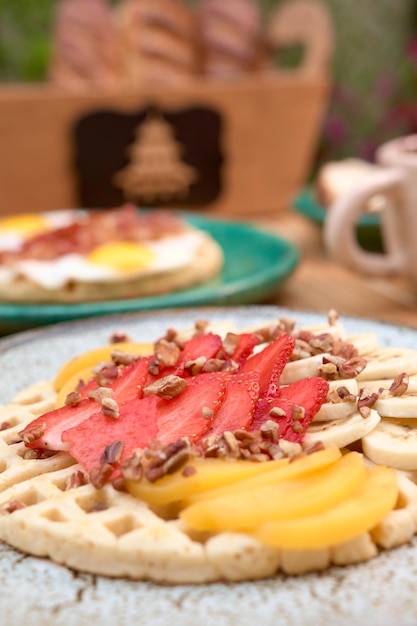 Delicious waffle with strawberry and peach on wooden table