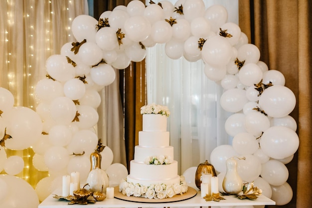 Вкусный свадебный банкет торт на фоне воздушных шаров украшенный стол на свадьбу белые шары свечи осенние листья и тыквы осенняя локация и декор на хэллоуин день рождения
