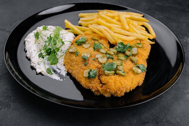 Delicious wiener hunter schnitzel with sauce and french fries closeup on a plate