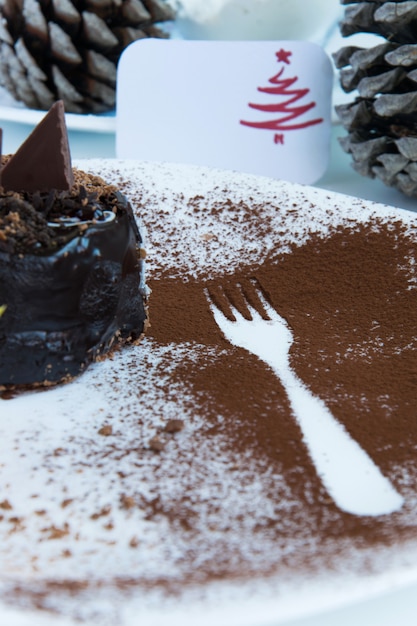 Delicious winter chocolate cake in a plate a fork outline cacao decoration and a greeting card