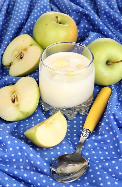 Delicious yogurt in glass with fruit on blue tablecloth