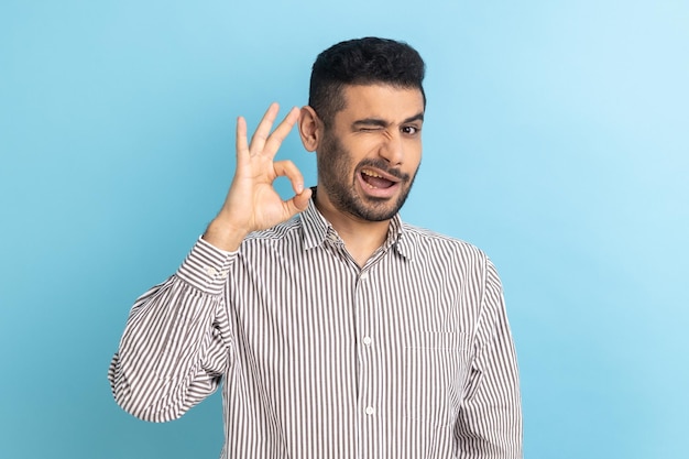 Delighted bearded businessman standing looking at camera showing Ok sign gesture