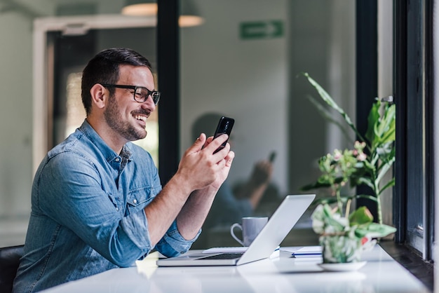 Delighted caucasian man with glasses looking at his phone log