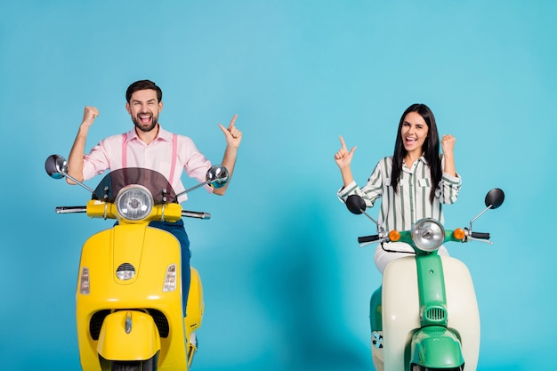 Delighted crazy two bikers riders drivers extreme sport lovers people celebrate victory motor bike ride lottery raise fists scream yes wear formalwear outfit isolated blue color wall