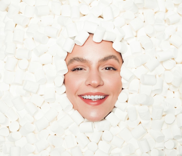 Delighted female in heap of marshmallows