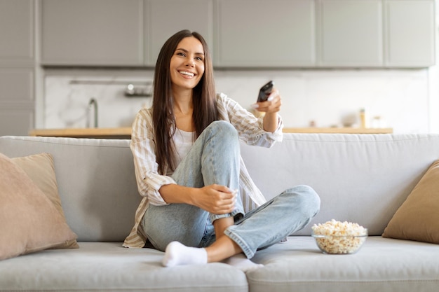 delighted female with bowl of popcorn at home watching her favorite shows