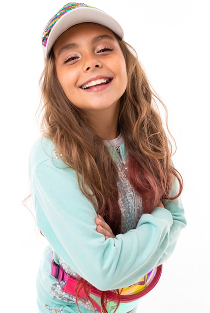 Delighted girl in sparkling clothes, cap and with waist bag isolated