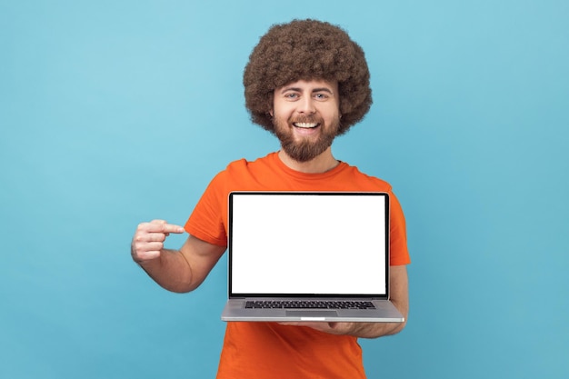 Delighted man standing showing empty display of laptop pointing at screen advertising area